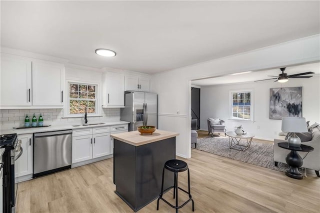 kitchen with light countertops, appliances with stainless steel finishes, open floor plan, white cabinets, and a kitchen island