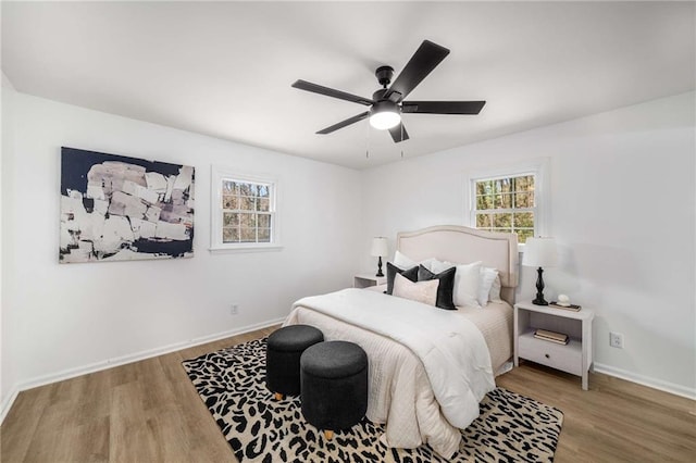 bedroom featuring multiple windows, baseboards, and wood finished floors