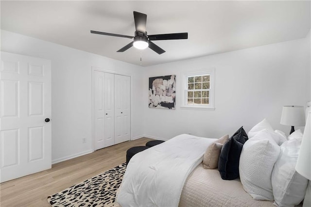 bedroom with ceiling fan, light wood finished floors, a closet, and baseboards