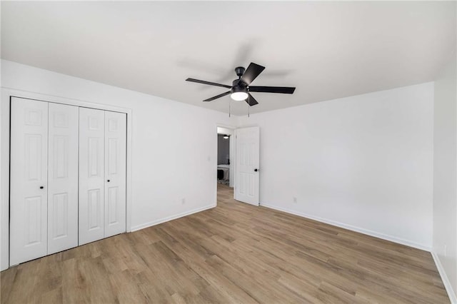 unfurnished bedroom featuring baseboards, ceiling fan, a closet, and light wood-style floors