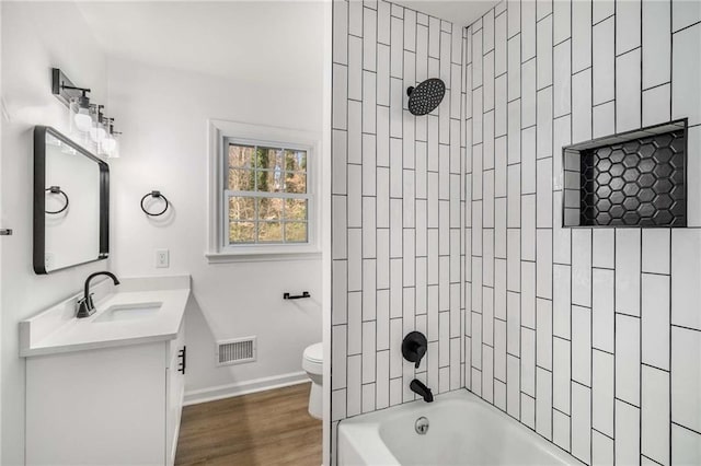 bathroom featuring toilet, wood finished floors, vanity, visible vents, and washtub / shower combination