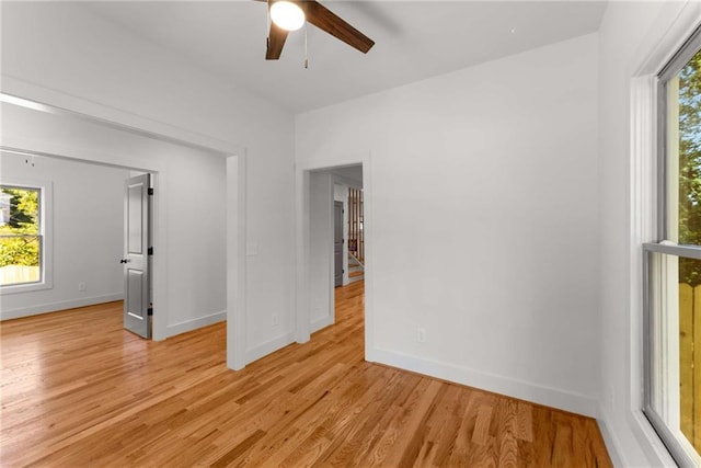 unfurnished room featuring light wood-style floors, plenty of natural light, and baseboards