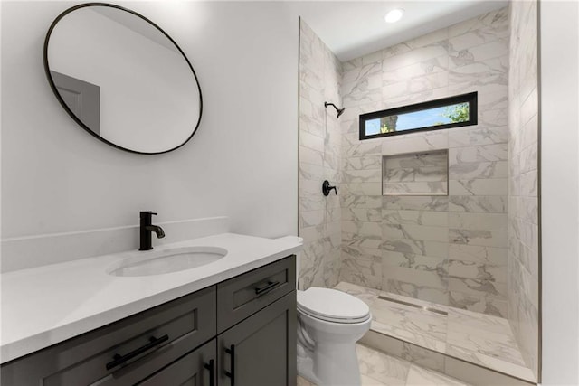 bathroom featuring marble finish floor, recessed lighting, toilet, a tile shower, and vanity