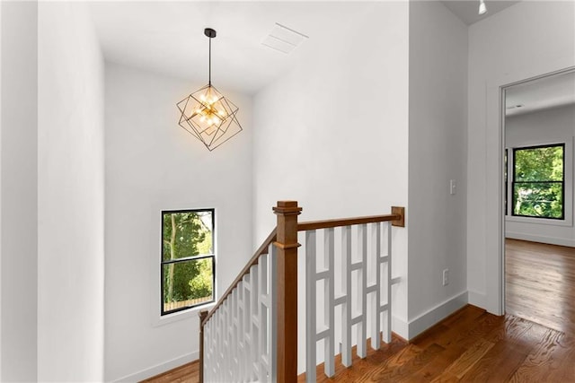 stairs featuring a chandelier, baseboards, and wood finished floors