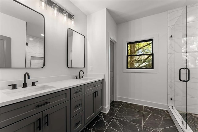 bathroom with marble finish floor, a shower stall, baseboards, and a sink