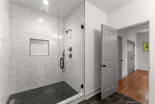 bathroom with marble finish floor, a stall shower, and baseboards