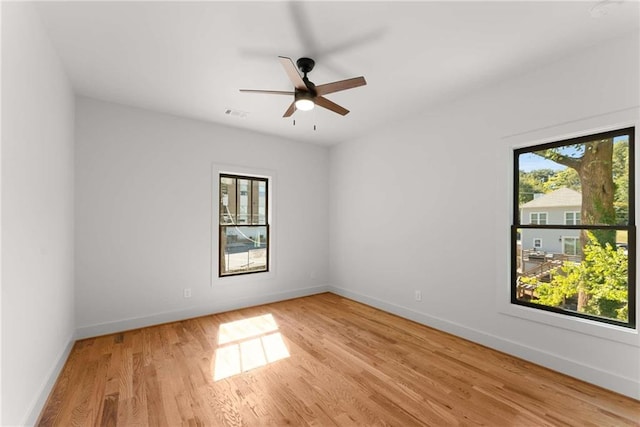 empty room featuring light wood-type flooring, a healthy amount of sunlight, and baseboards