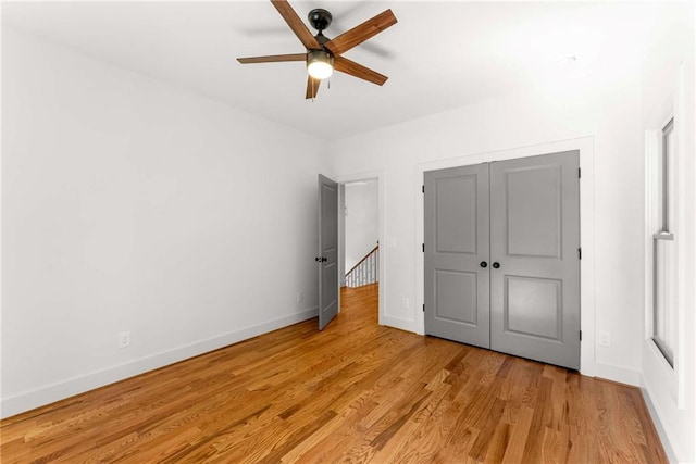 unfurnished bedroom featuring a ceiling fan, a closet, light wood-style flooring, and baseboards