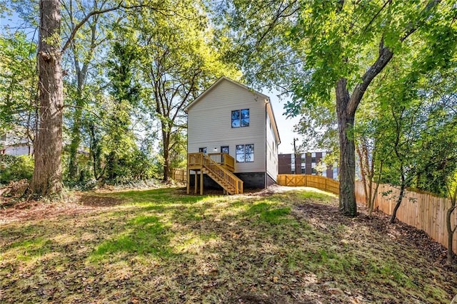 back of property with fence, a wooden deck, and stairs