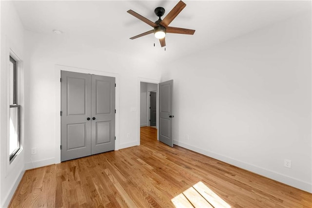 unfurnished bedroom featuring light wood-type flooring, a closet, ceiling fan, and baseboards