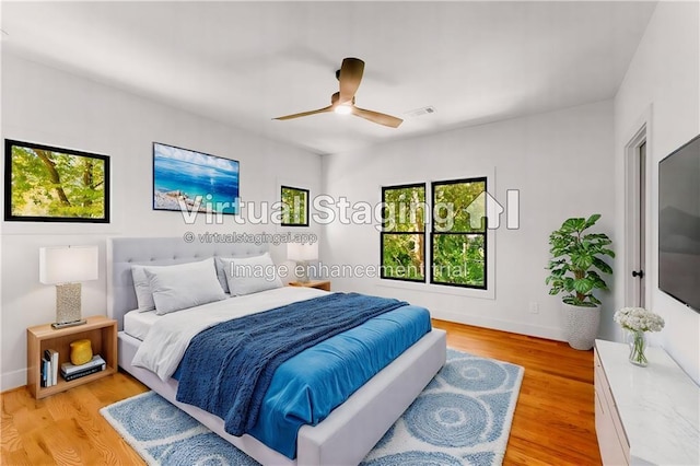 bedroom with light wood-type flooring, ceiling fan, visible vents, and baseboards