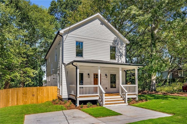 view of front of property featuring covered porch, fence, and a front yard