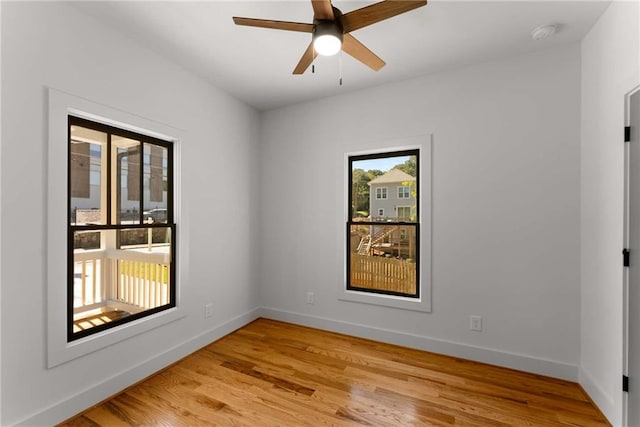 spare room with light wood finished floors, ceiling fan, and baseboards