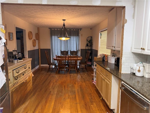 dining area with dark wood-style floors, a textured ceiling, and wainscoting