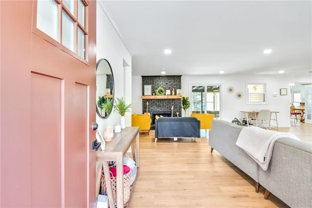 living room with a brick fireplace and light hardwood / wood-style floors