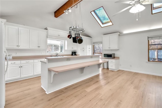 kitchen with sink, ceiling fan, light hardwood / wood-style flooring, and white cabinetry