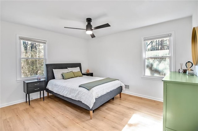 bedroom with multiple windows, ceiling fan, and light wood-type flooring