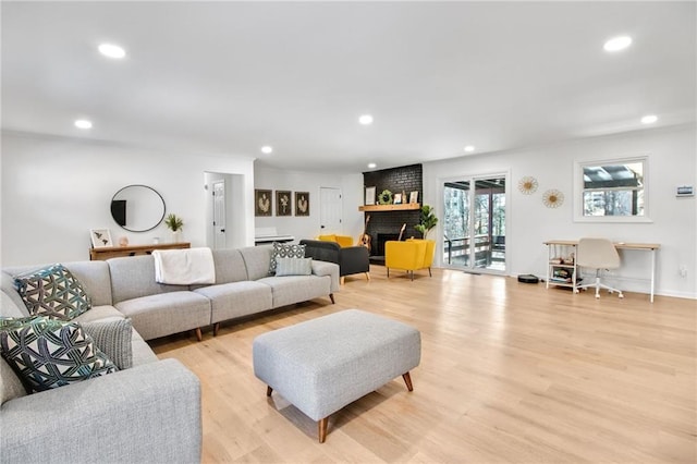 living room with light wood-type flooring and a brick fireplace