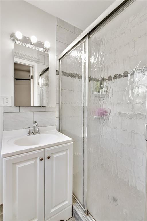 bathroom with tile walls, an enclosed shower, vanity, and decorative backsplash