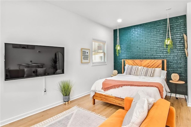 bedroom with brick wall and hardwood / wood-style floors