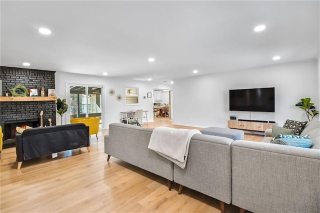 living room with a brick fireplace and light hardwood / wood-style floors