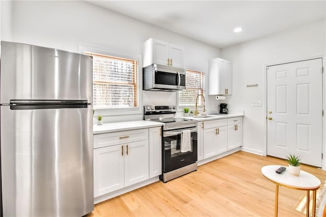 kitchen featuring stainless steel appliances, white cabinets, sink, and a wealth of natural light