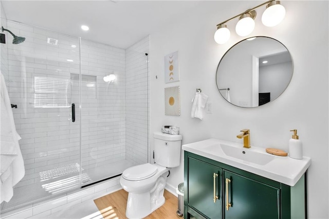 bathroom featuring toilet, vanity, and a shower with shower door