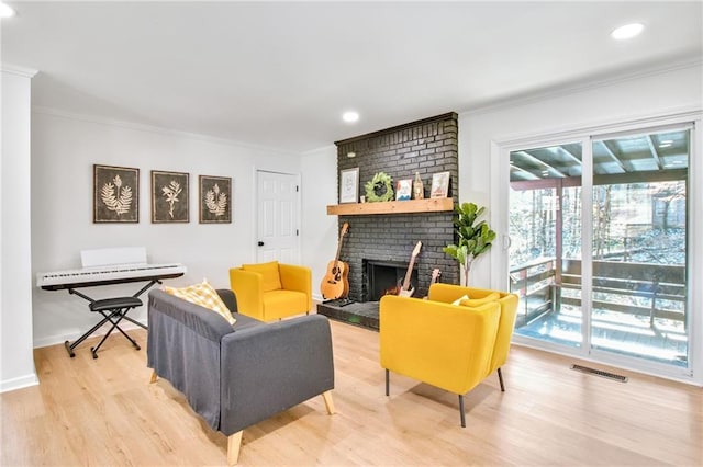 living room with ornamental molding, light wood-type flooring, and a fireplace