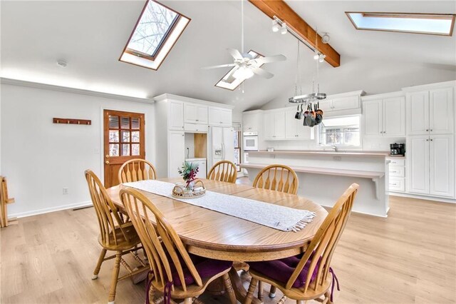 dining area with ceiling fan, light wood-type flooring, rail lighting, and vaulted ceiling with skylight