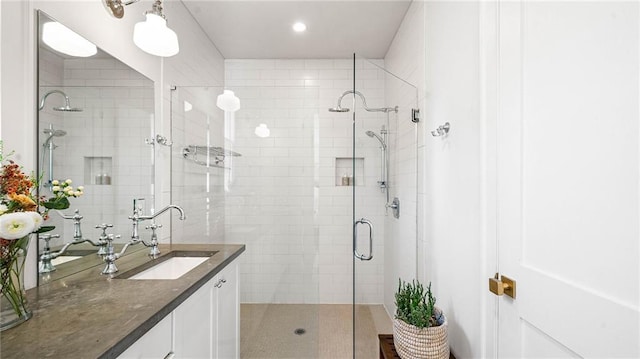 bathroom featuring a shower with door and vanity