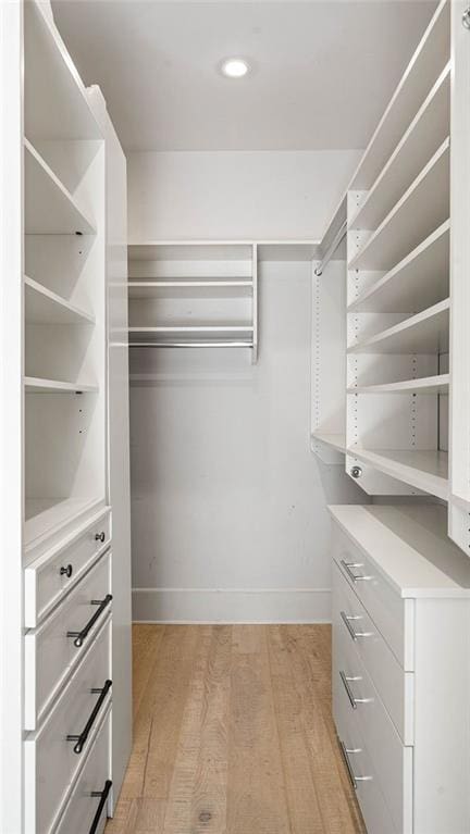 walk in closet with light hardwood / wood-style floors