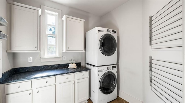 washroom with cabinets and stacked washing maching and dryer