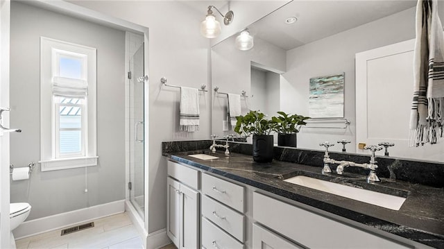 bathroom featuring vanity, a shower with shower door, and toilet