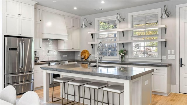 kitchen featuring white cabinetry, custom range hood, premium appliances, and a kitchen island