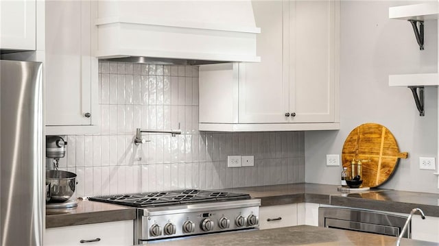 kitchen featuring appliances with stainless steel finishes, decorative backsplash, white cabinetry, and custom range hood