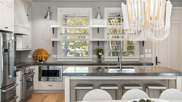 kitchen featuring white cabinetry, stainless steel appliances, light hardwood / wood-style flooring, and a kitchen bar