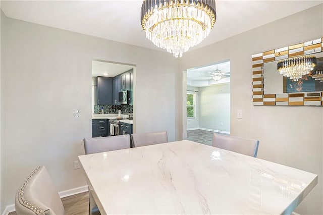 225 Hardwood Dr, Covington, GA 30016 - dining space featuring a chandelier, baseboards, a ceiling fan, and wood finished floors