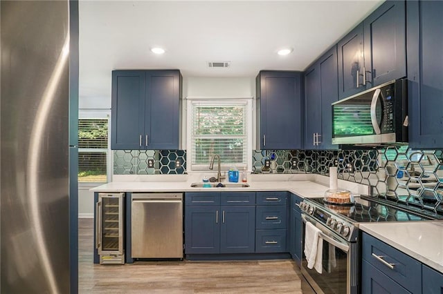 225 Hardwood Dr, Covington, GA 30016 - kitchen with appliances with stainless steel finishes, a sink, wine cooler, light countertops, and light wood-style floors