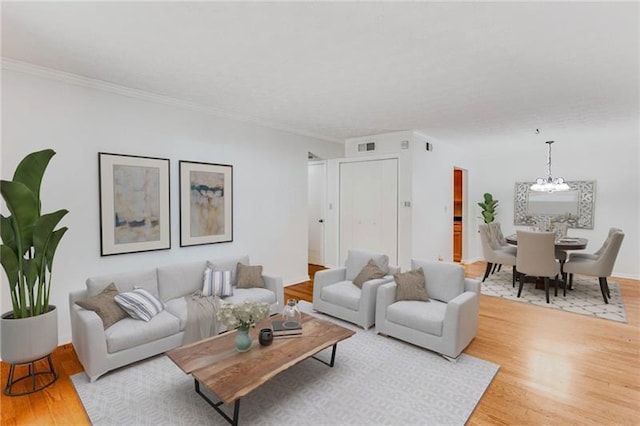 living room featuring crown molding, a chandelier, and hardwood / wood-style floors