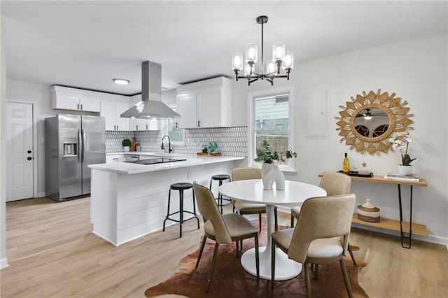 dining space with sink, a notable chandelier, and light hardwood / wood-style flooring