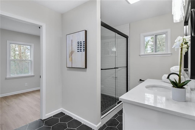 bathroom with a healthy amount of sunlight, an enclosed shower, tile patterned flooring, and vanity