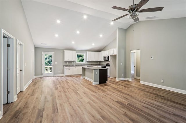 kitchen featuring light hardwood / wood-style flooring, white cabinetry, a center island, high vaulted ceiling, and stainless steel appliances