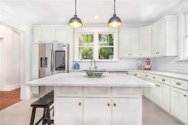 kitchen with white cabinetry, a kitchen island, and light stone counters