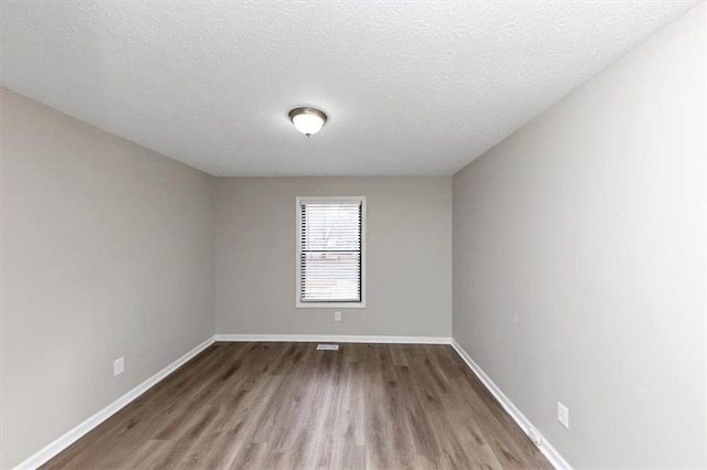 spare room featuring hardwood / wood-style flooring and a textured ceiling