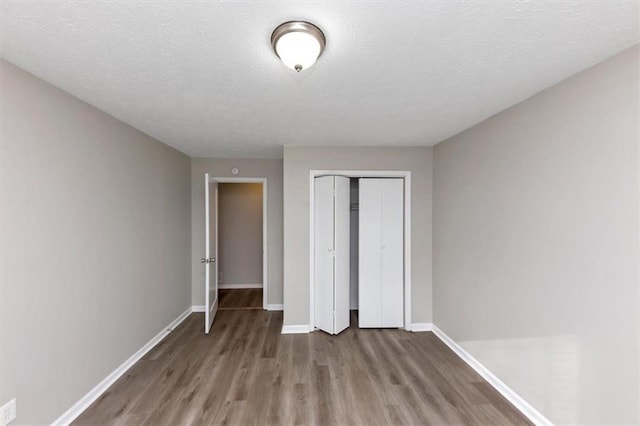 unfurnished bedroom featuring hardwood / wood-style floors, a closet, and a textured ceiling