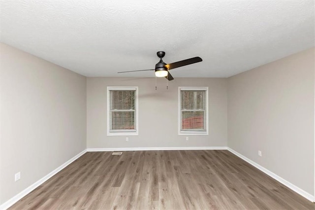 empty room with ceiling fan, a textured ceiling, and light wood-type flooring