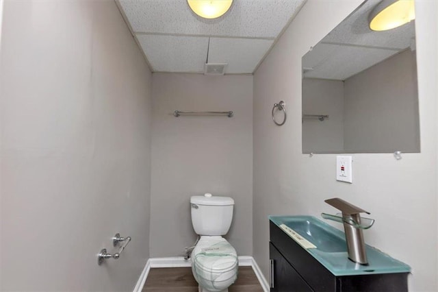 bathroom featuring vanity, hardwood / wood-style flooring, a paneled ceiling, and toilet