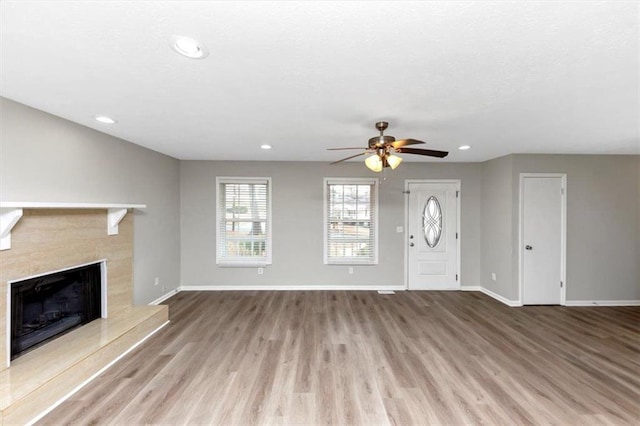 unfurnished living room featuring ceiling fan, a fireplace, and light hardwood / wood-style flooring