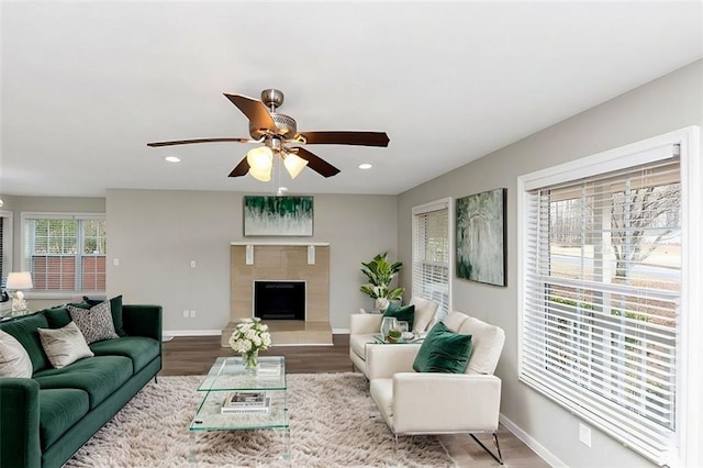 living room with hardwood / wood-style flooring, a tile fireplace, and ceiling fan