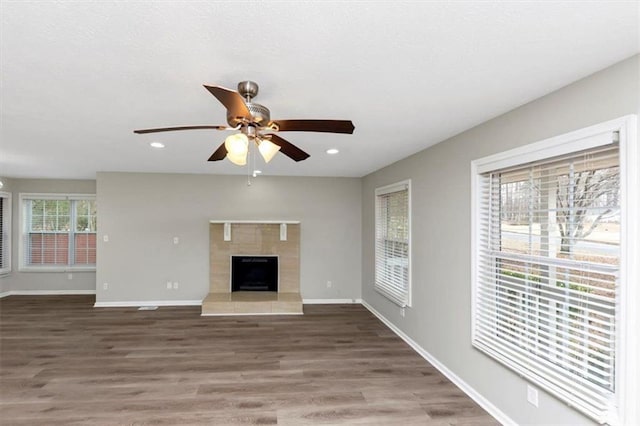 unfurnished living room with ceiling fan, wood-type flooring, and a fireplace